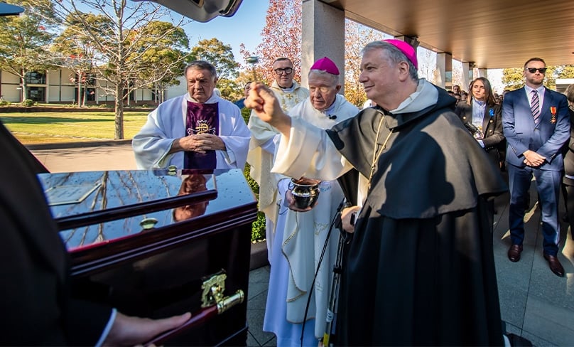 Archbishop Anthony Fisher OP sprinkles holy water on the coffin of Peter O'Meara outside the Mary Mother of Mercy Chapel in Rookwood Cemetery on 17 June. Photo: Giovanni Portelli