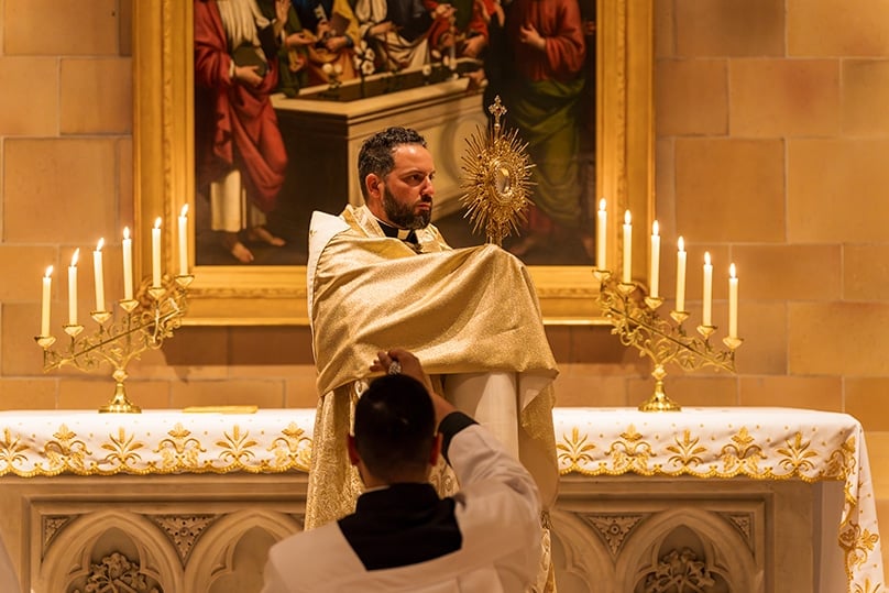 Fr Lewi Barakat, an Assistant Priest at St Mary's Cathedral, raises the Blessed Sacrament during adoration in the crypt of St Mary's Cathedral. Photo: Patrick J Lee