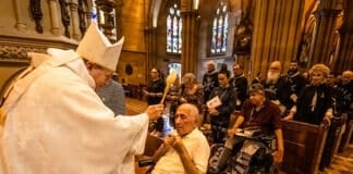 Archbishop Anthony Fisher OP blesses a man with holy water during the Lourdes Day Mass at St Mary’s Cathedral on 2 December. Photo: Giovanni Portelli