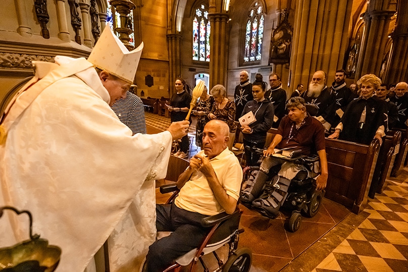 Archbishop Anthony Fisher OP blesses a man with holy water during the Lourdes Day Mass at St Mary’s Cathedral on 2 December. Photo: Giovanni Portelli